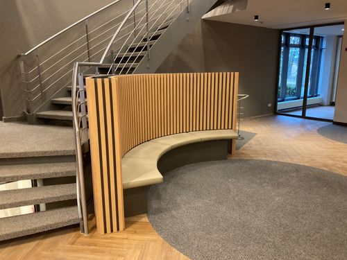Foyer in einem Hotel, runde Sitzgelegenheit, dahinter verläuft eine Stiege