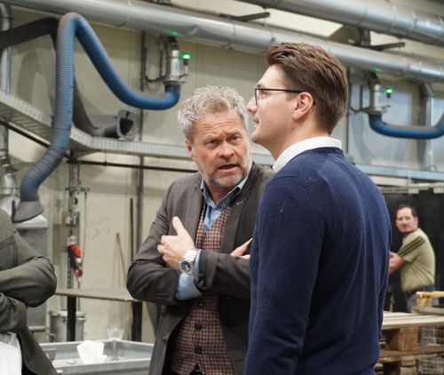 Niko Swatek und Geschäftsführer Bernd Lambauer stehen in einer Produktionshalle und führen ein Gespräch