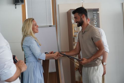 Eine Frau und ein Mann geben sich die Hand, die Frau gratuliert dem Mann zur bestandenen Lehrabschlussprüfung