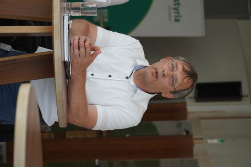 Mann steht bei Tisch und erklärt etwas