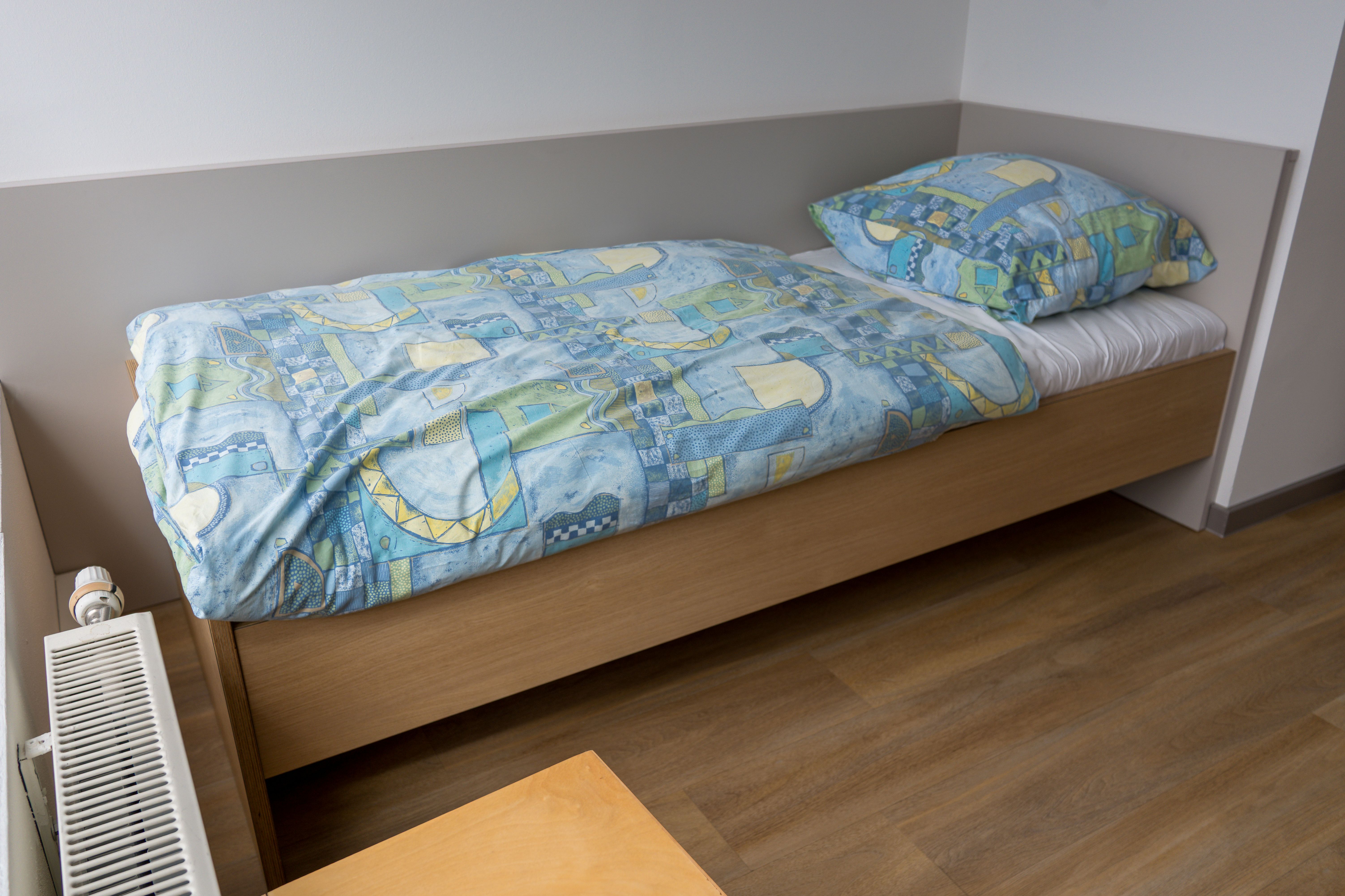 Einzelbett in einem hellen Raum mit blauer Bettwäsche