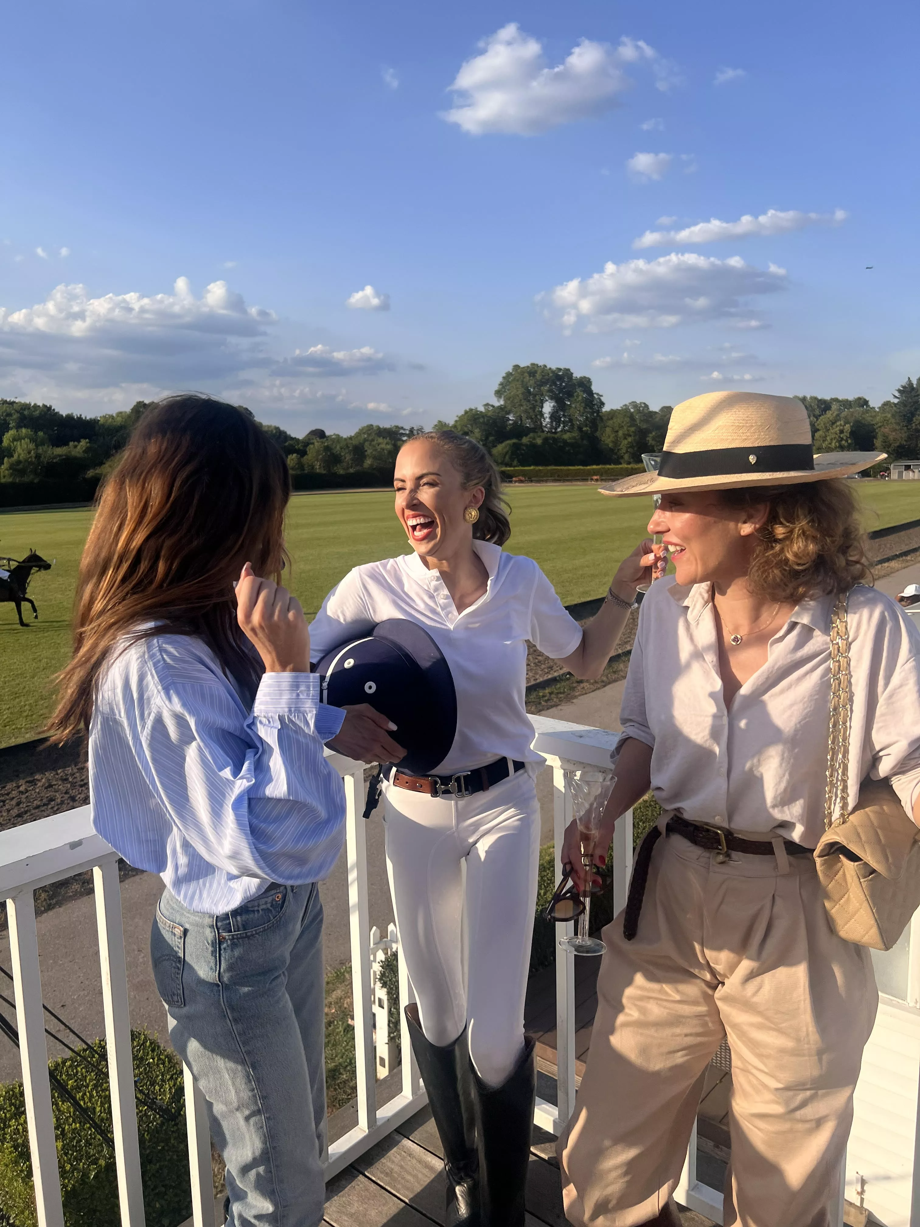 Three women laughing together at a polo match