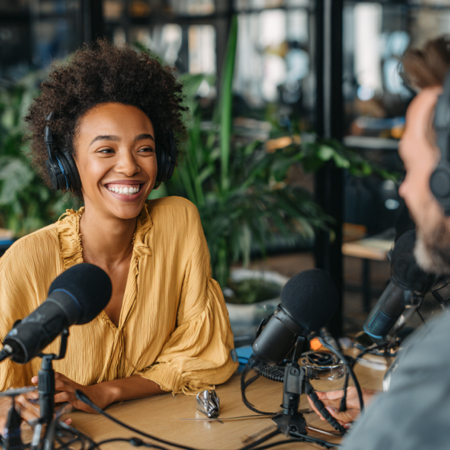 Two professionals recording a podcast with microphones and headphones in a modern office studio, representing media planning and buying in digital broadcasting and content strategy.