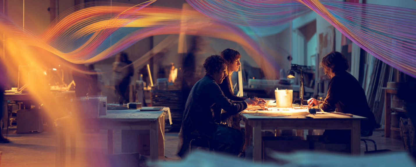 Creative team collaborating in a dynamic studio environment with glowing light trails symbolizing the energy and innovation of graphic design services