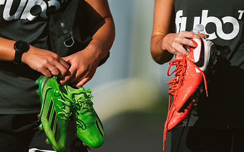Close-up of athletes holding brightly colored cleats, symbolizing athlete endorsements and the influence of branded gear in sports marketing.