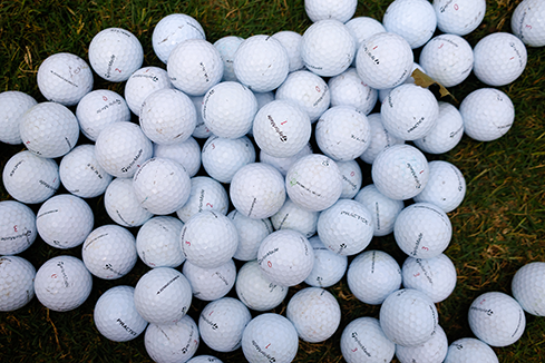 Pile of golf balls on grass, symbolizing pop-ups and street teams that drive hands-on brand engagement in sports marketing.