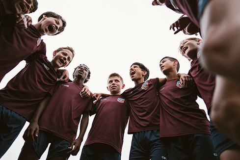 Youth soccer team in a huddle, symbolizing experiential installations that foster connection, teamwork, and immersive sports brand experiences.