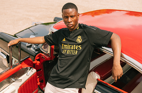 Athlete leaning against a classic car in a branded soccer jersey, representing influence and athlete strategy in modern sports marketing and brand partnerships.