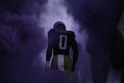 Football player walking through dramatic smoke and light, symbolizing content planning & campaign development that builds anticipation and drives audience engagement