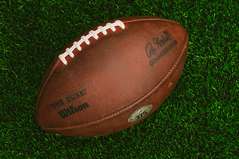 Close-up of a football on green turf, representing sports brand strategy, positioning, and the power of iconic athletic branding.