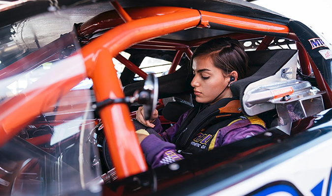 Woman race car driver preparring for a race inside the driver's seat, symbolizing strategy, teamwork, and preparation
