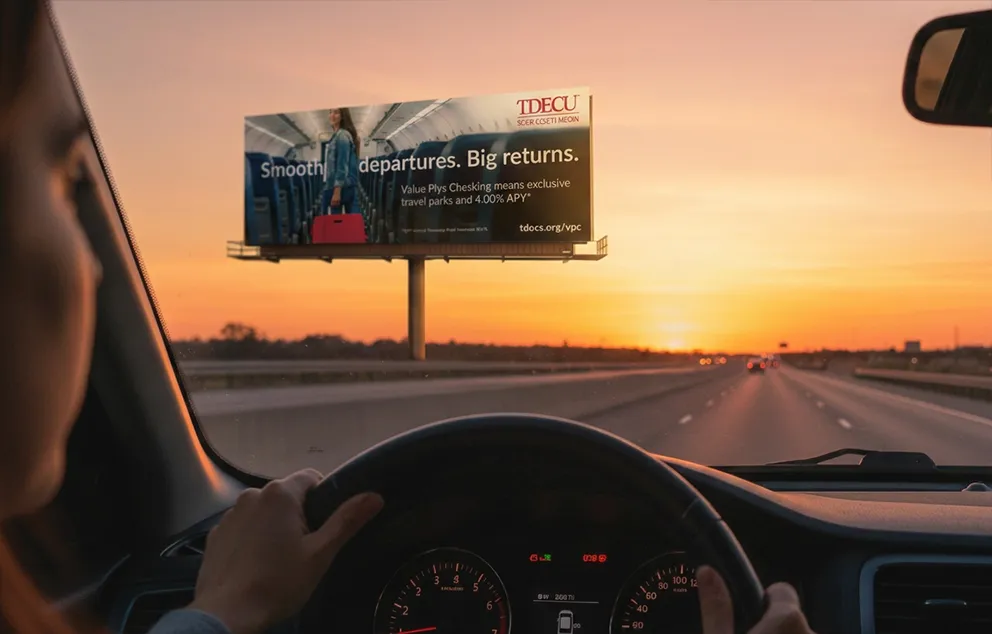 Image of a woman driving down a highway, looking at a billboard that features effective brand design.