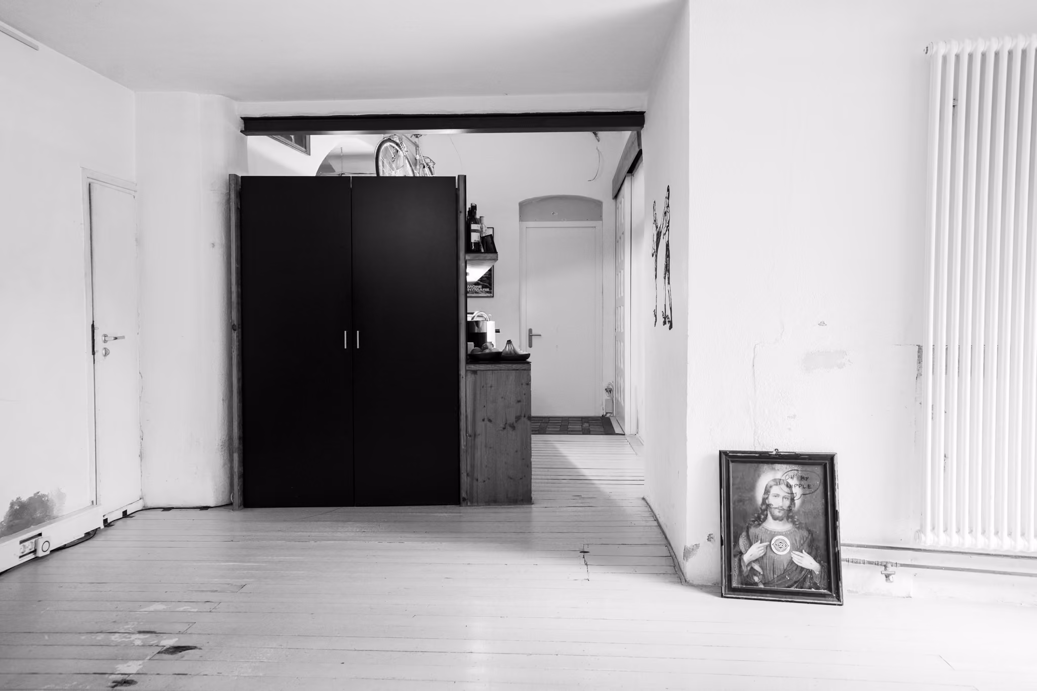 Eingangsraum des Super Offices, mit Küchenzeile, Tür, Heizung und einem Bild an der Wand.