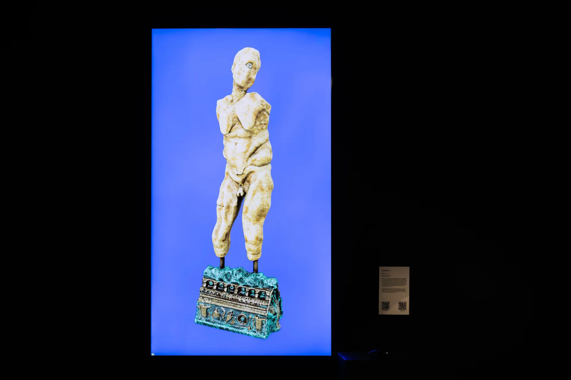 MUD Foundation Auriea Harvey’s *Cyclops v1*, 2021, featuring a digital sculpture of a fragmented classical human figure displayed against a vivid blue background, with a decorative sculptural base.
