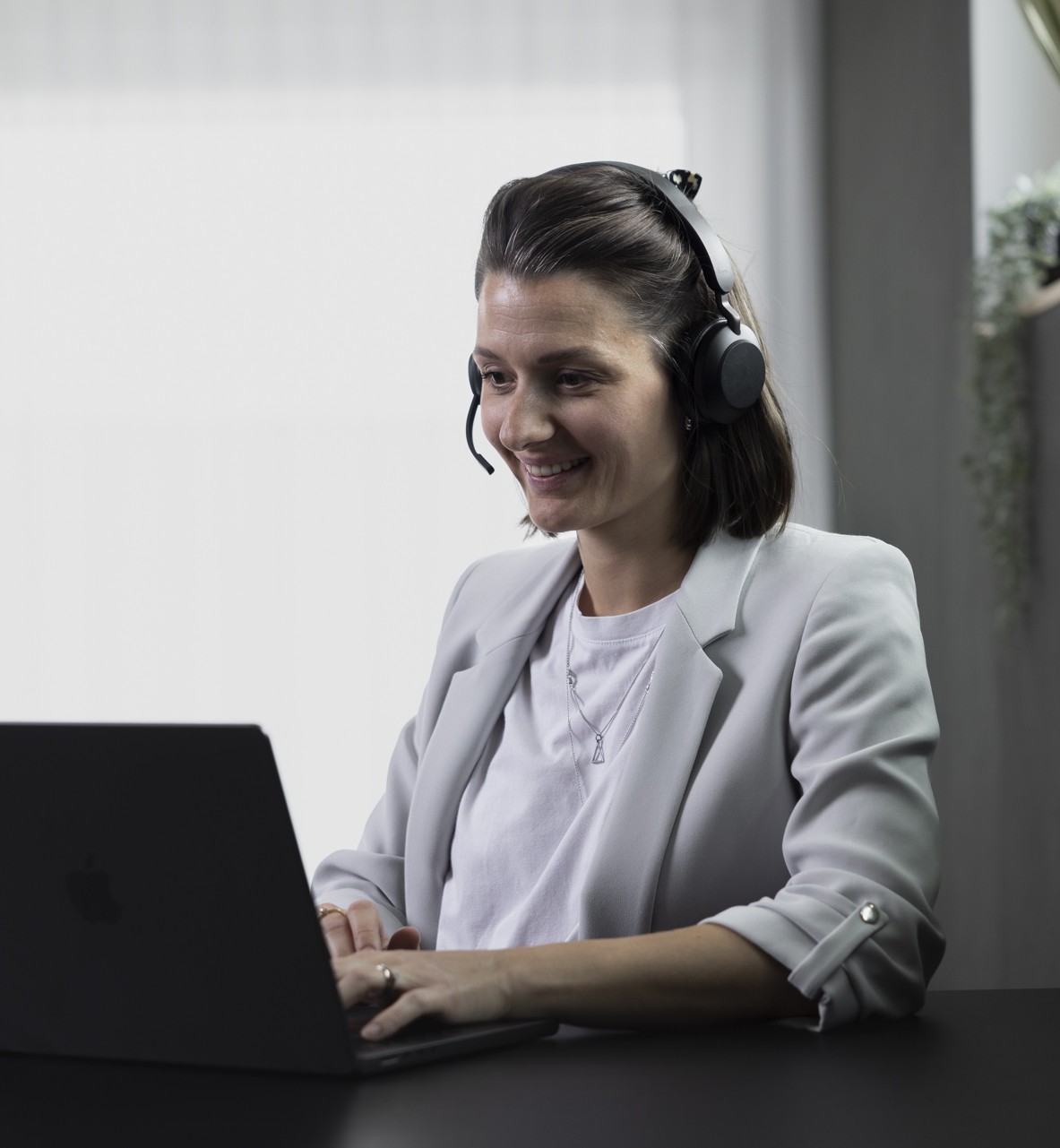 Eine Frau trägt Kopfhörer und lächelt, während sie an einer SEO Strategie arbeitet.