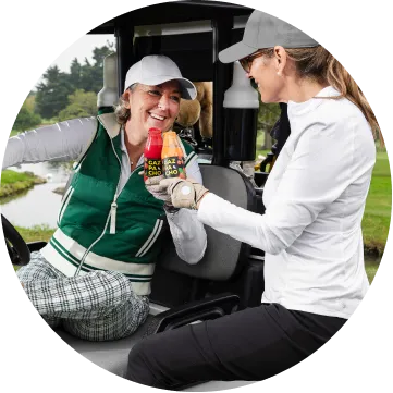 image of two women in a golf car drinking Gazpacho