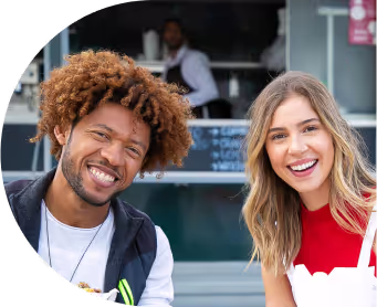 Positive young multiracial friends eating fast food and drinking beer in outdoor cafe