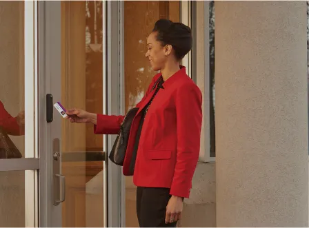 A woman in a red jacket is holding a card in front of a door.