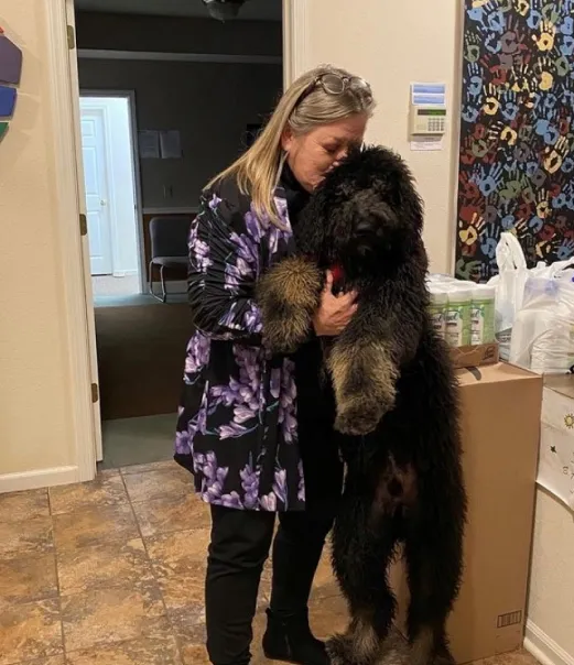 A woman holding a black dog.