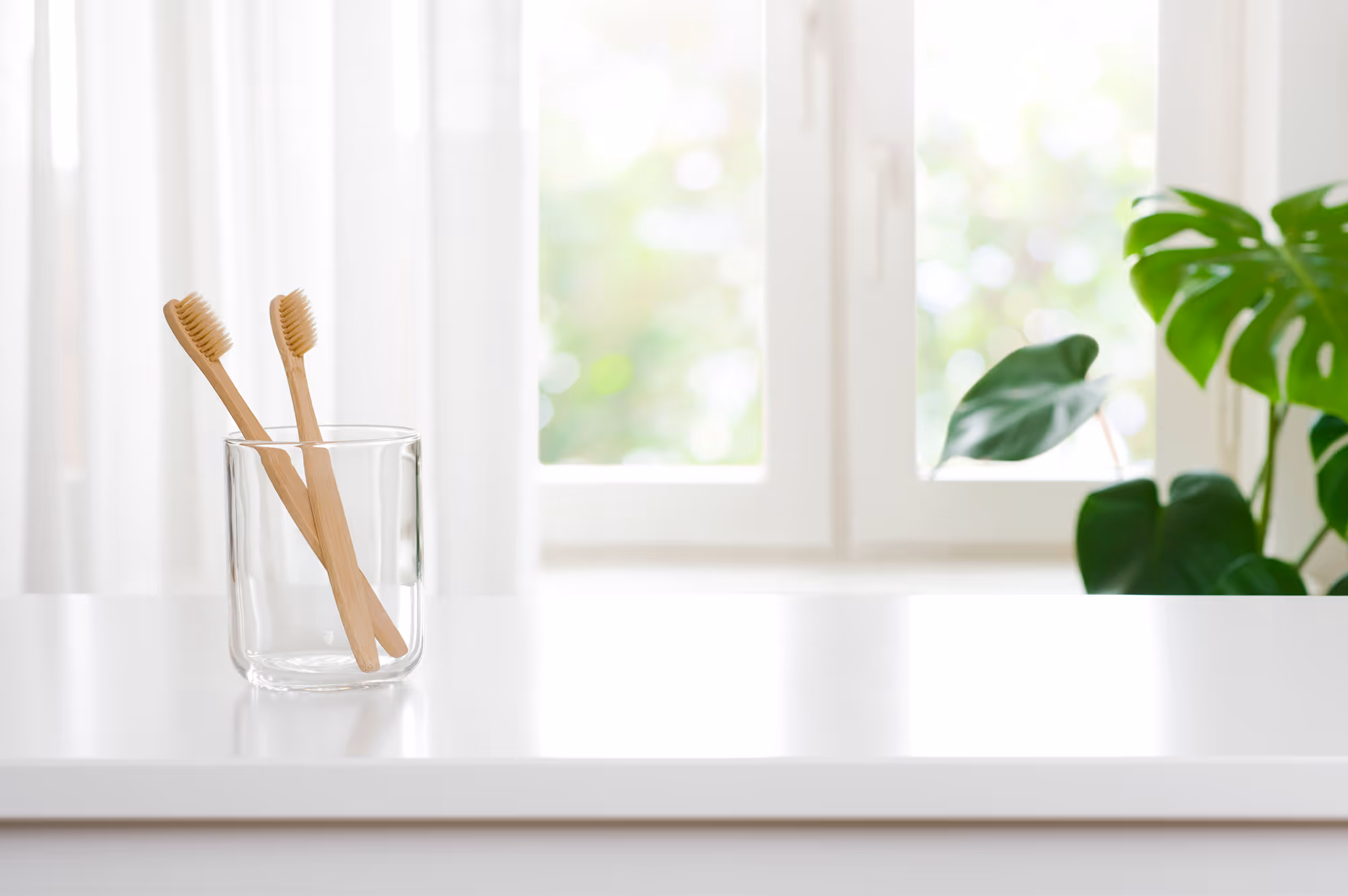 Two toothbrushes in a glass on a counter.