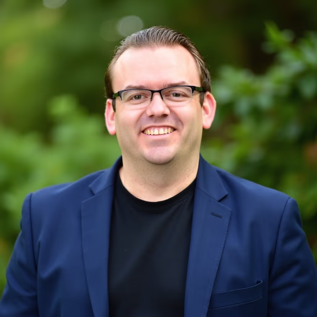 Mat Nelson smiling in a blazer against a green background, representing digital marketing expert in PPC and SEO services.