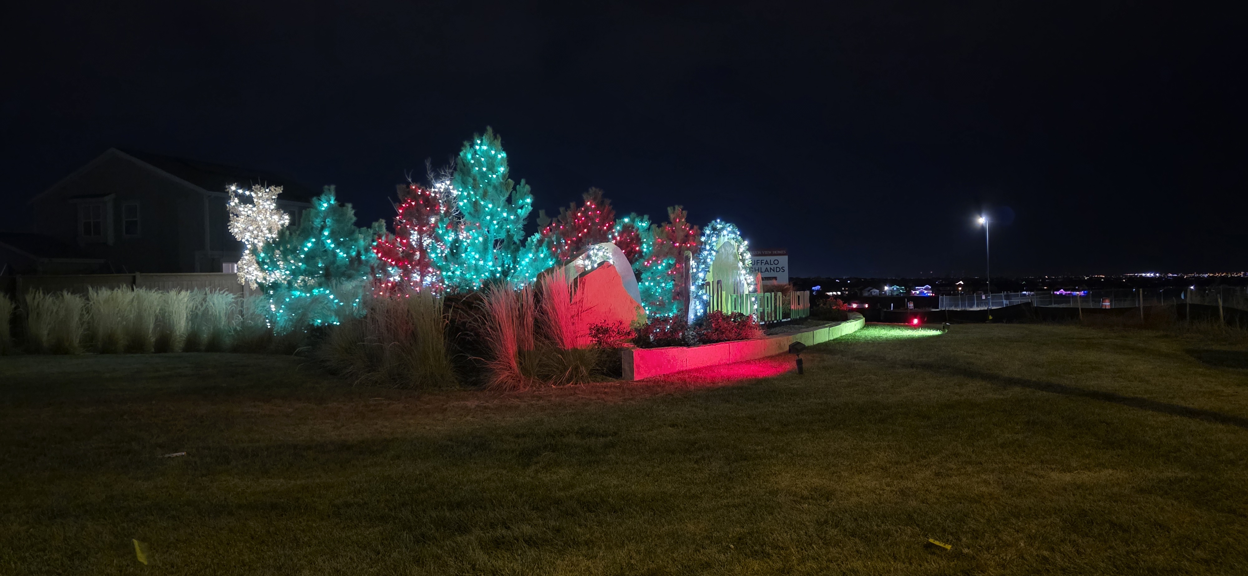 Red, green and white Christmas lighting around a Commerce City community monument and landscape