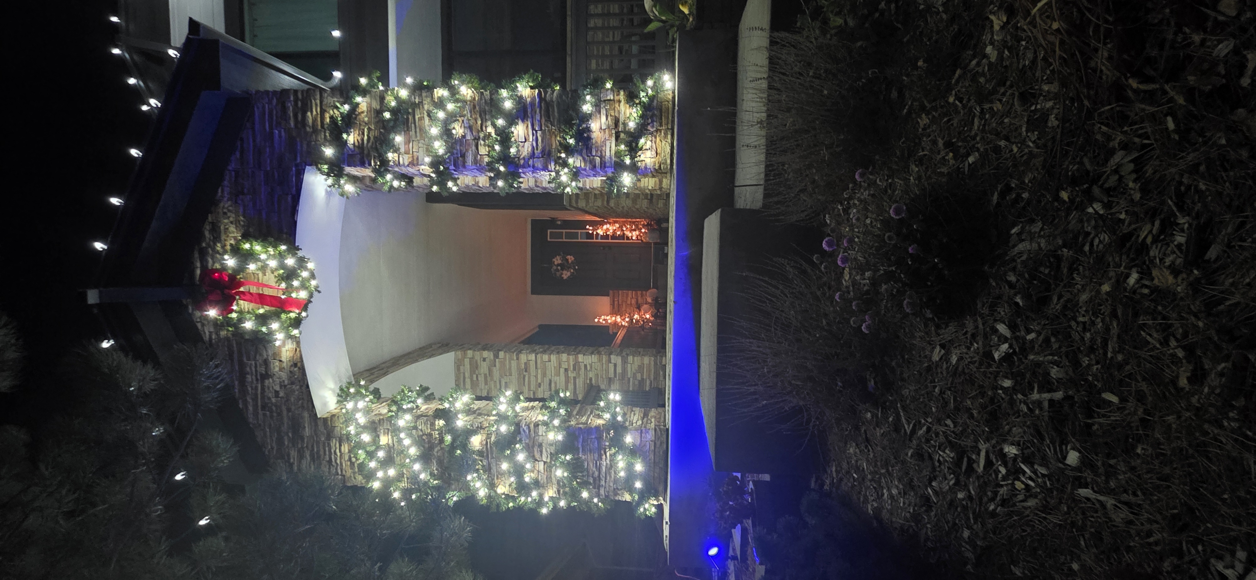 Residential Christmas entrance decorated with illuminated garland and a holiday wreath