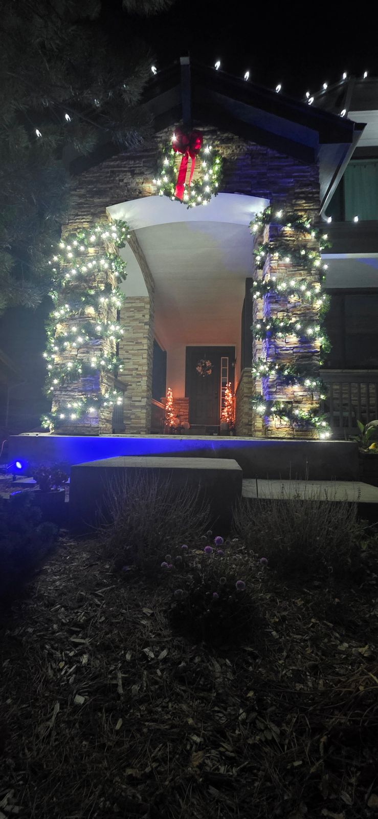 Residential Christmas entrance decorated with illuminated garland and a holiday wreath