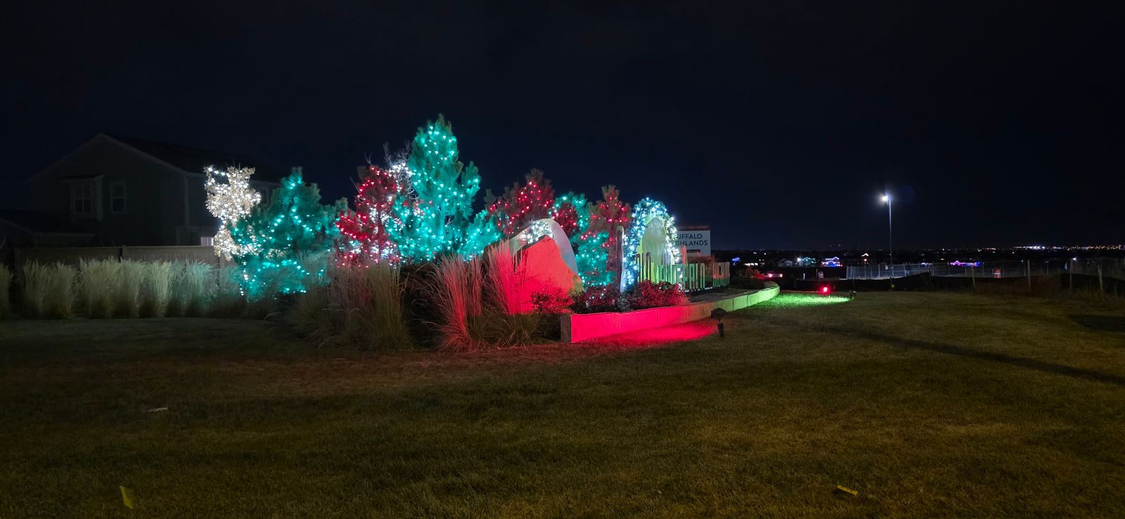 Red, green and white Christmas lighting around a Commerce City community monument and landscape