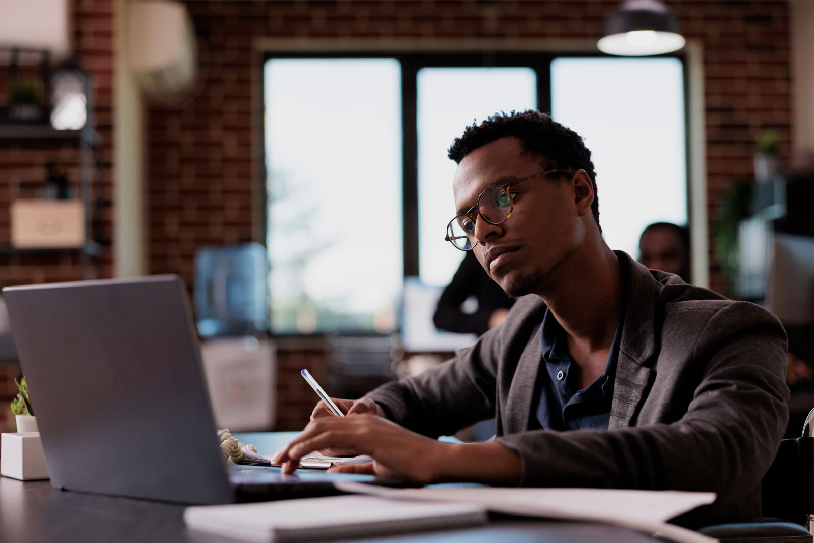 A man is sitting at a table in front of two laptops.