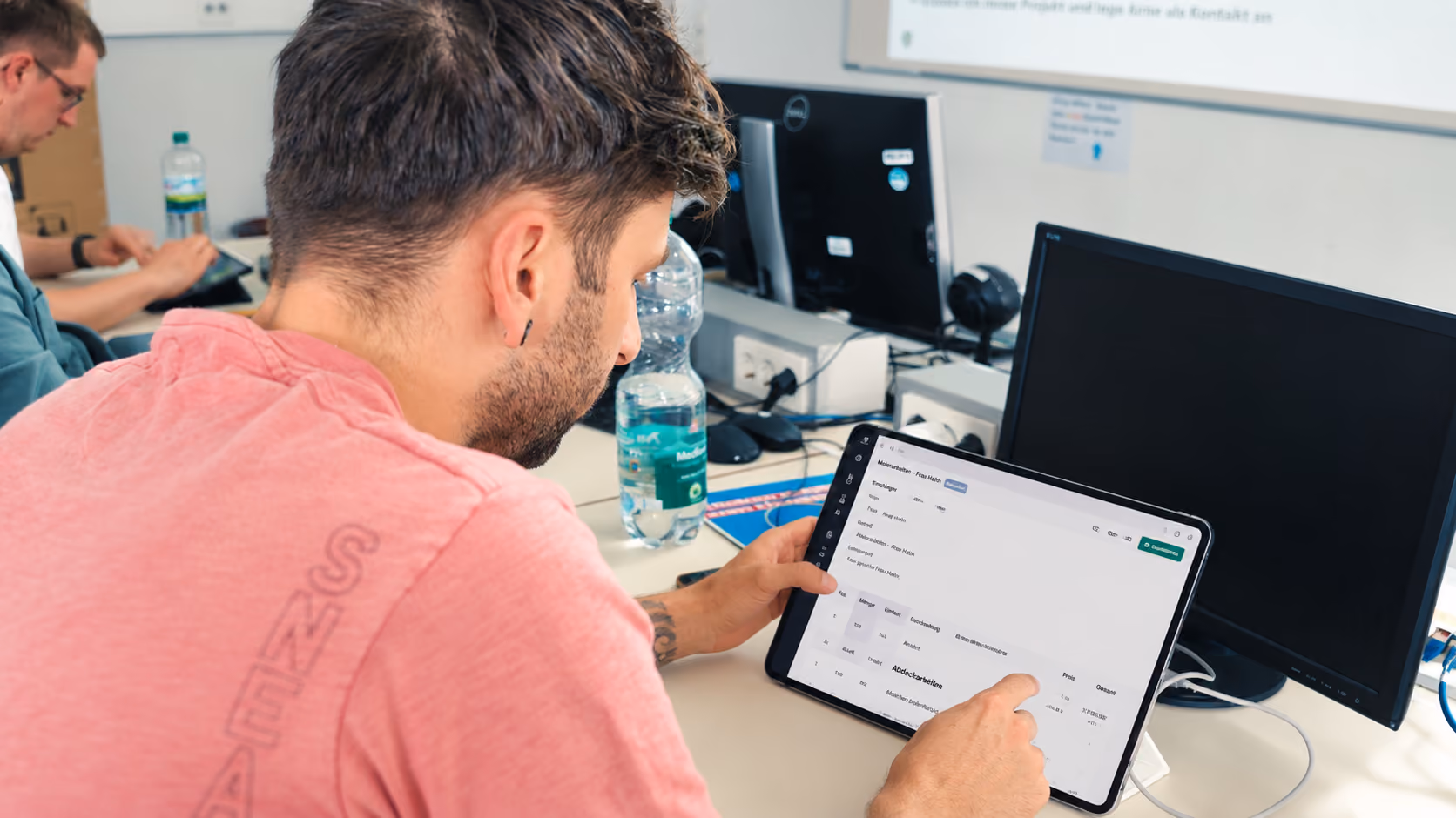 Ein Meisterschüler nutzt die plancraft-Software auf einem Tablet in einem Klassenzimmer, um sich mit moderner Handwerker-Software vertraut zu machen.