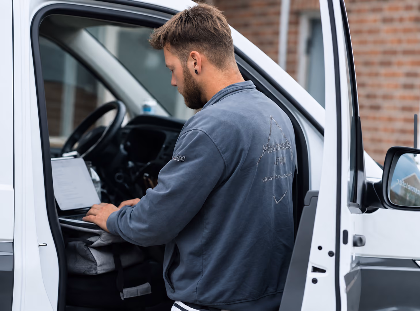 Ein Handwerker arbeitet mit der plancraft Handwerker Software auf einem Laptop im Fahrerbereich seines Transporters.