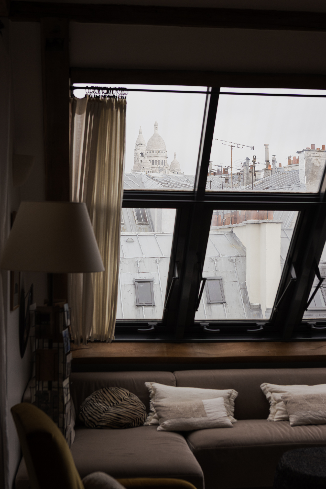 Duplex parisien rénové, issu de la réunion de chambres de service, avec verrières sur mesure, matériaux en bois et pierre, et espaces lumineux sous pente.