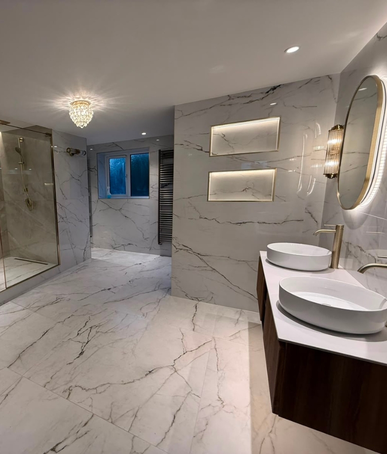 Modern bathroom with round lit mirror, vessel sink, wall-mounted toilet and glass shower