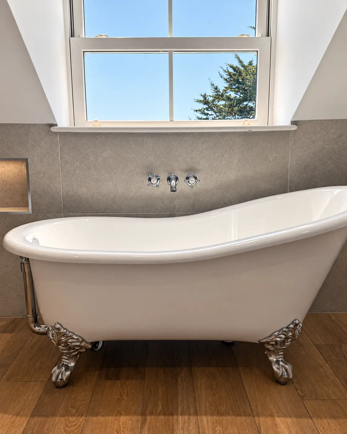 Freestanding roll-top bath beneath a large bathroom window