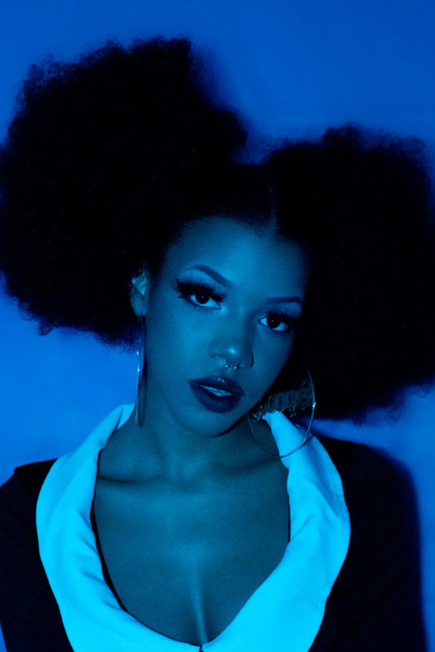 Portrait of person with voluminous curly hair against blue neon background