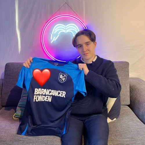 Tim rangström holding a barncancer fonden shirt