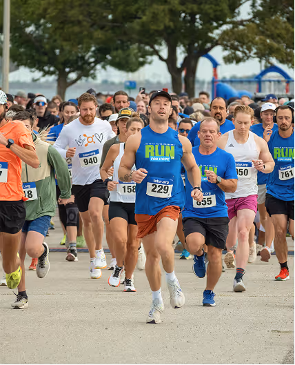 Group of runners participating in the run for hope on a paved path with trees and playground equipment in the background.