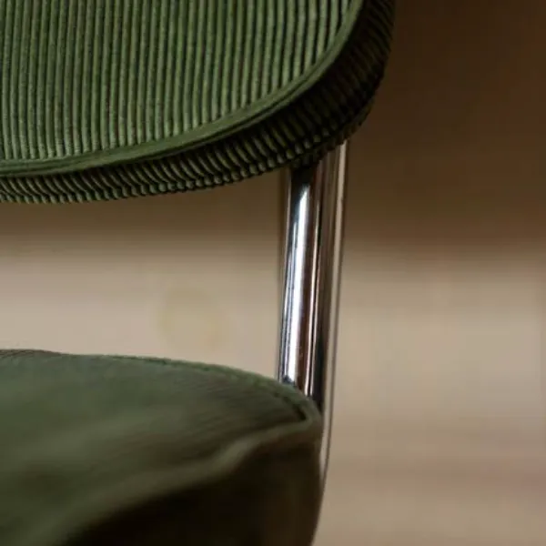 Photo en gros plan d’une chaise en velours vert, mettant en valeur les matières nobles sélectionnées par Momerable pour ses aménagements.