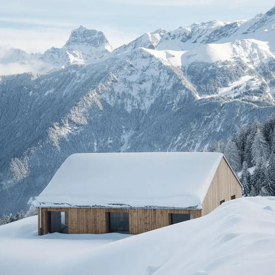 Photo d’un chalet Swiss Cabin sous la neige, illustrant le design montagnard moderne et l’architecture préfabriquée signée Momerable.