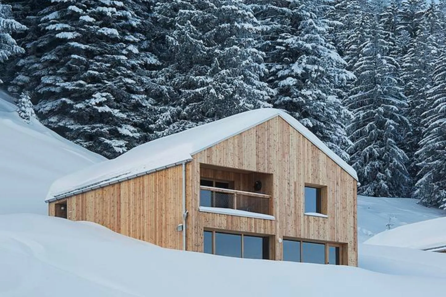 Photo d’une façade enneigée d’un chalet Swiss Cabin, mettant en valeur le confort hivernal et la qualité architecturale développés par Momerable.