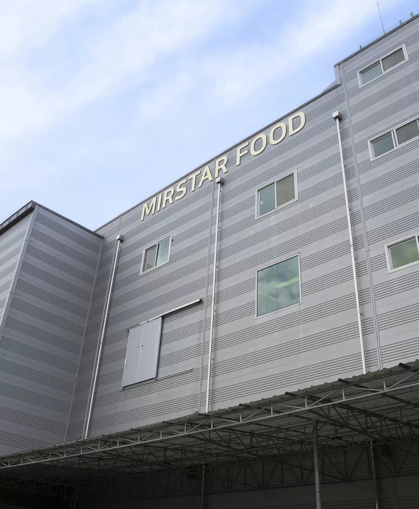 파란 하늘을 배경으로 한 회색 금속 외벽의 미르스타푸드 건물 외관.