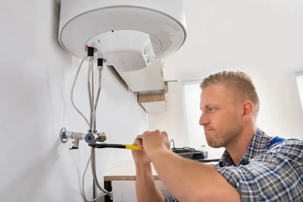 A plumber is using a tool to replace a water heater system