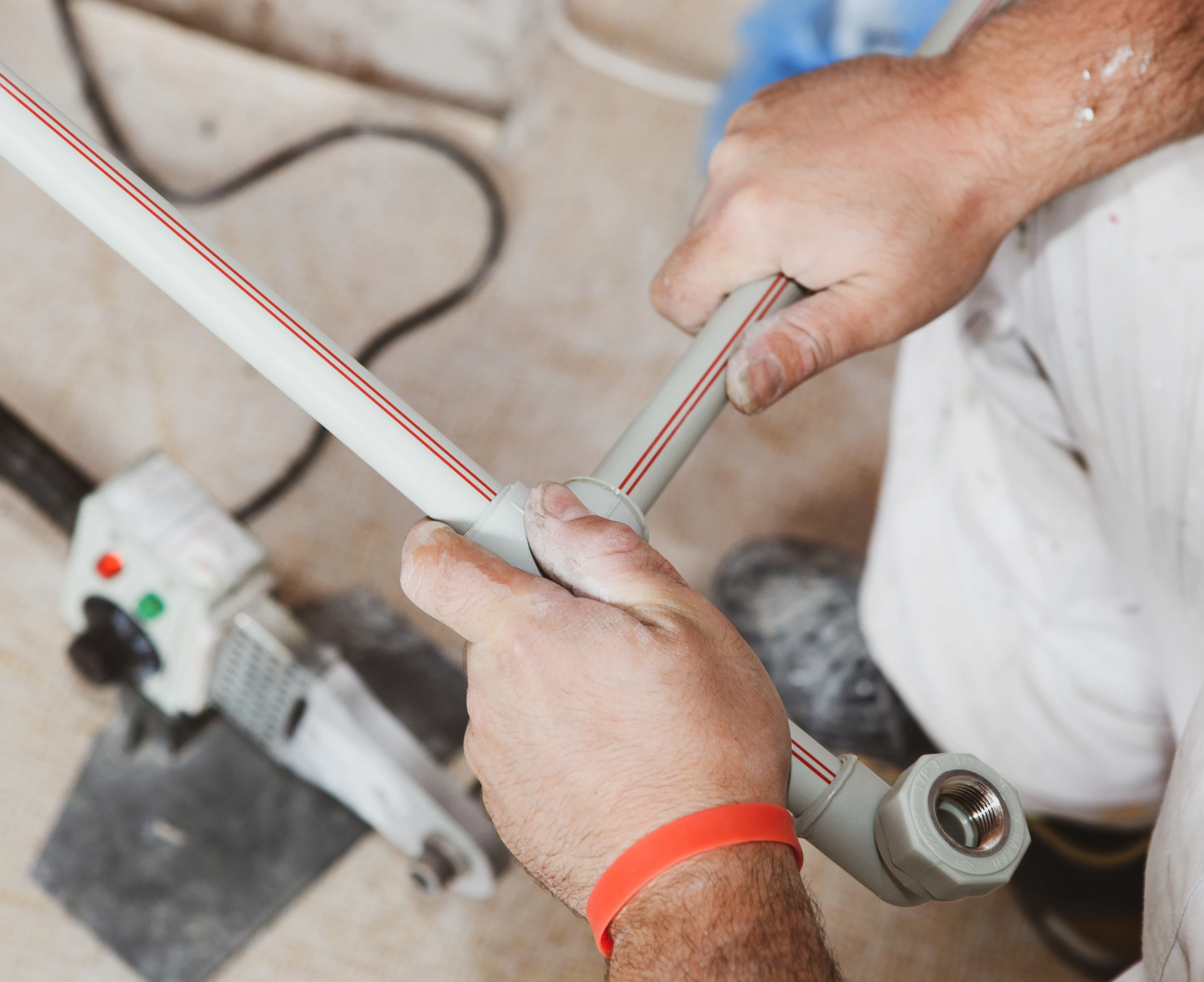 Close-up of hands fitting plastic pipes with connectors on a workshop floor