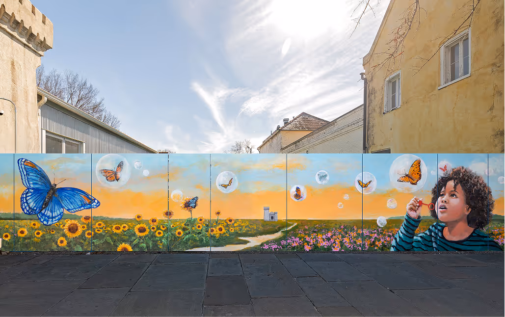 Large wall in an urban area displaying a mural of a child and butterflies