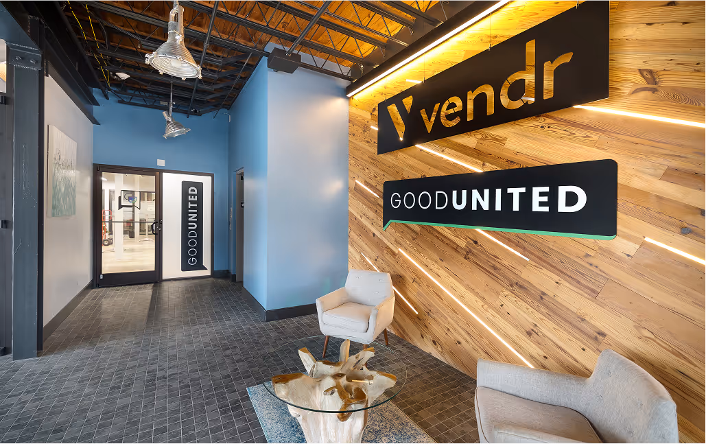 Reception area of the Vendr GoodUnited building featuring a large wooden wall displaying the business logos