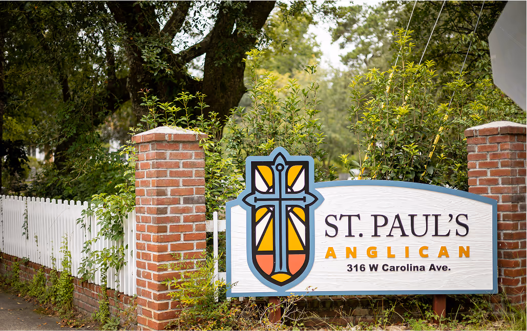 Wooden sign on a classic brick fence displaying the St. Paul's Anglican logo