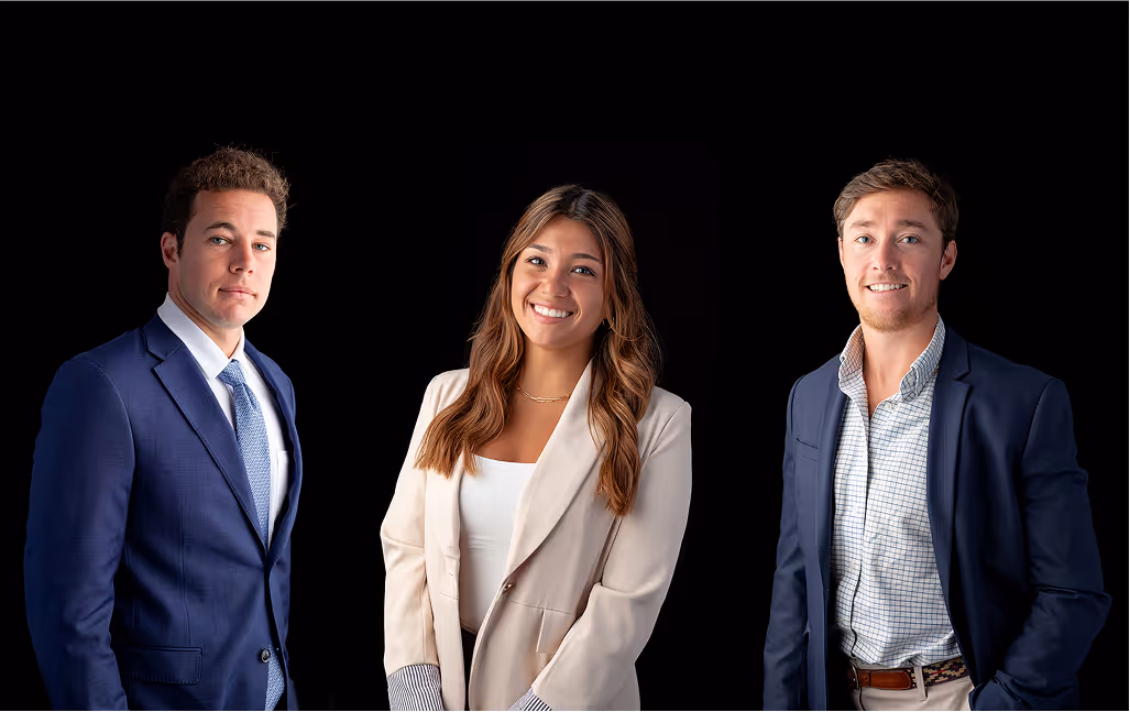 Three sharply-dressed young business professionals posing for a photo against a black background