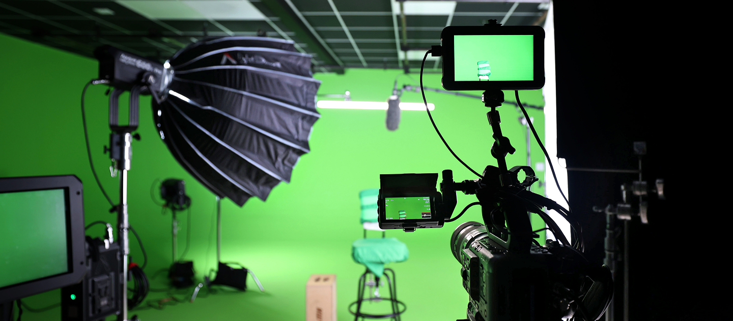Green screen video production studio setup with camera equipment, lighting, and microphone ready for filming.