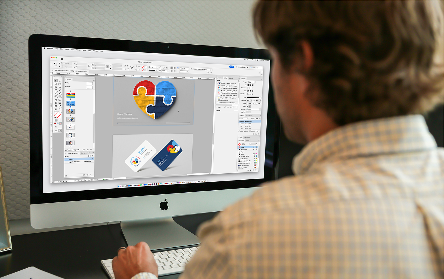 Graphic designer working on a branding project using Adobe software, editing a colorful puzzle heart logo on an iMac screen